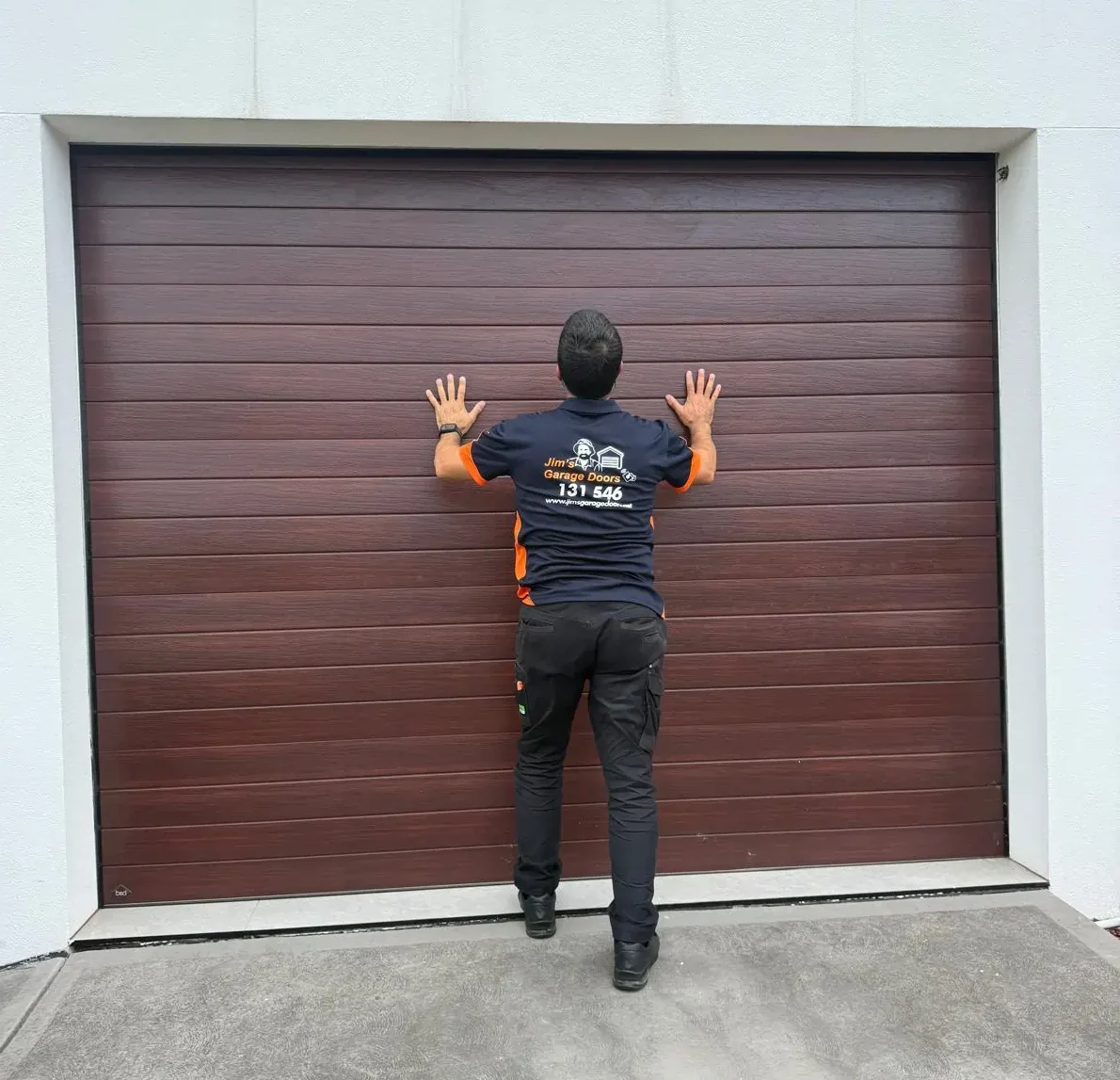 Technician testing garage door movement manually by pushing sectional door to check operation and resistance