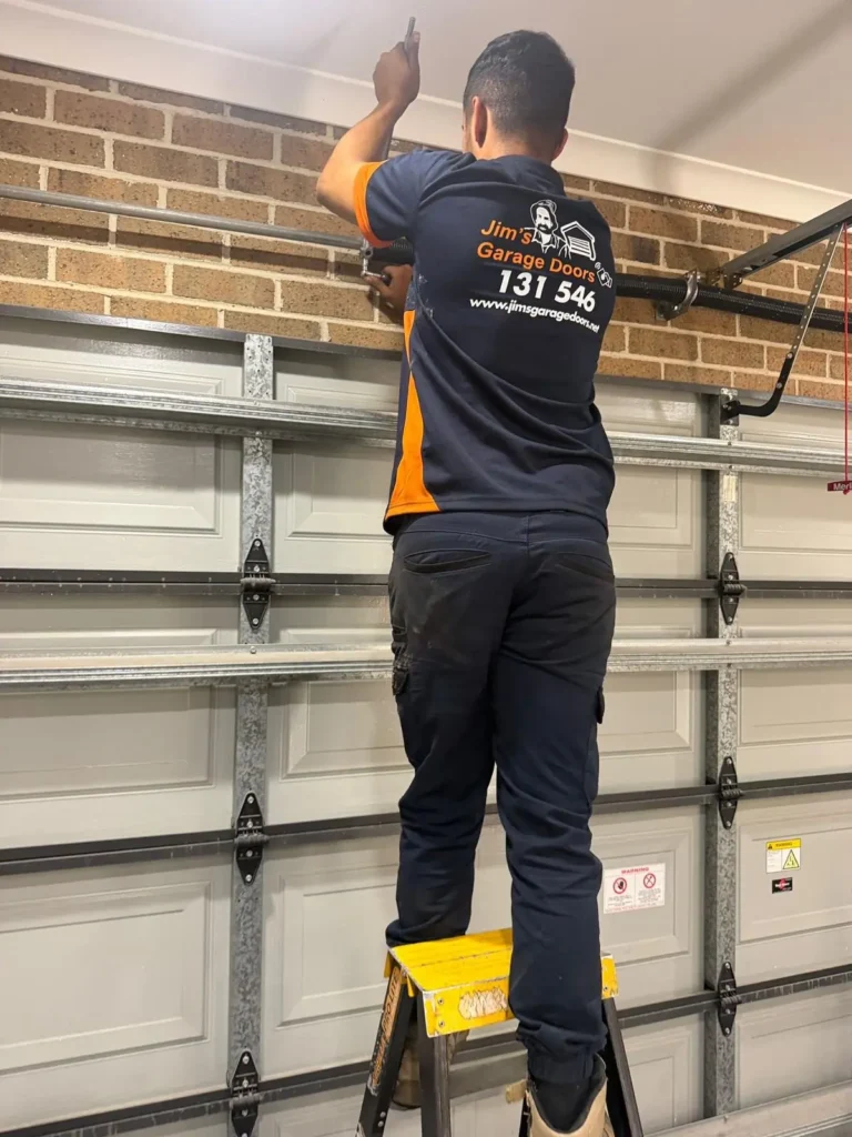 Technician adjusting garage door torsion spring and shaft assembly to restore proper door balance and operation