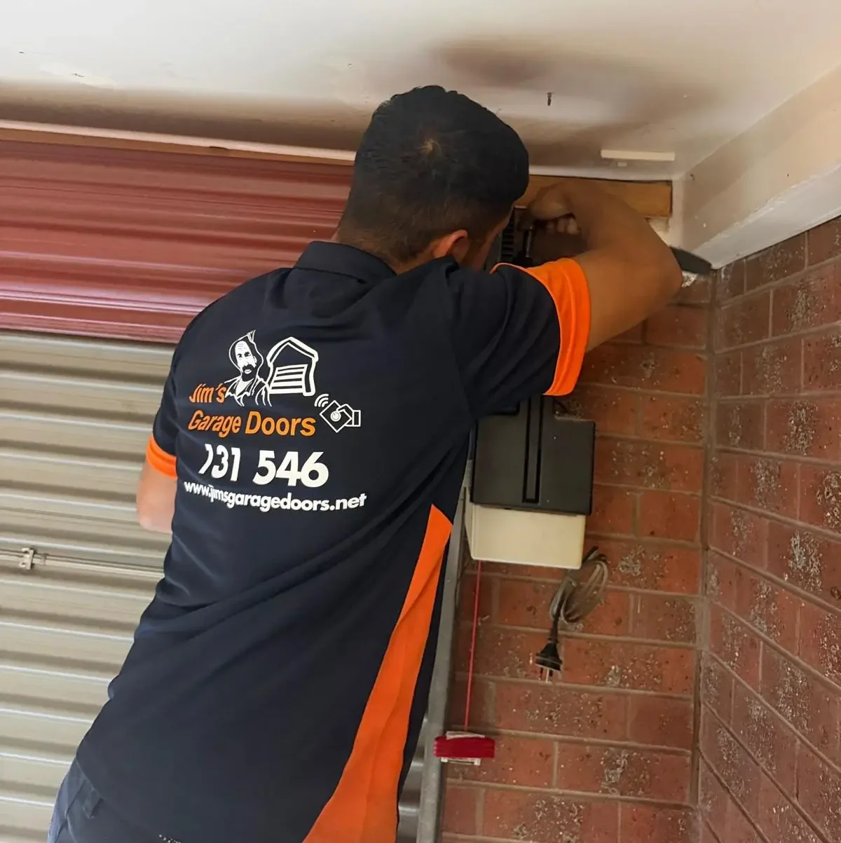 Technician repairing roller door opener by adjusting side mounted motor unit and control system