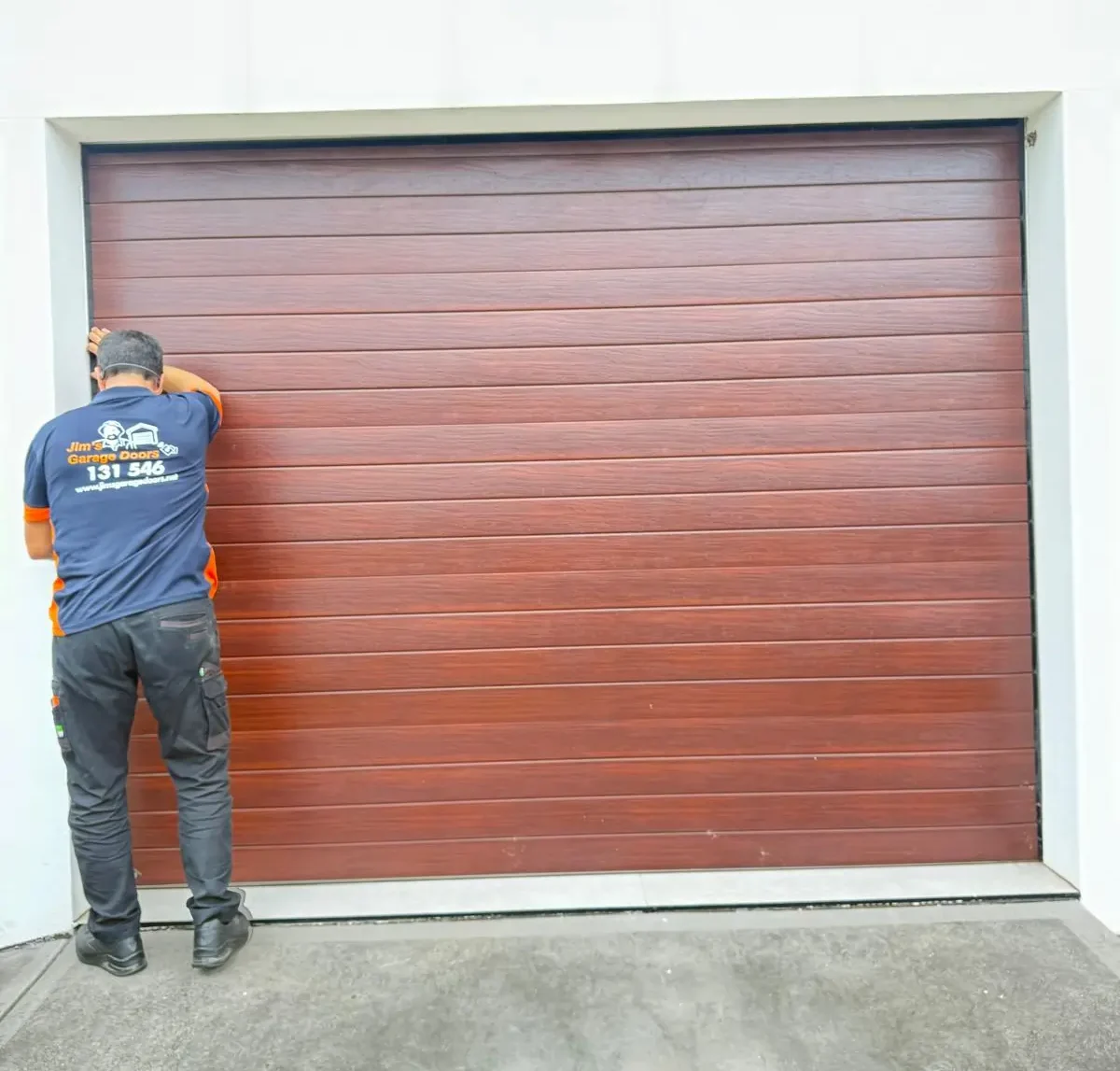 Technician inspecting sectional garage door alignment and edge positioning for proper closing and operation