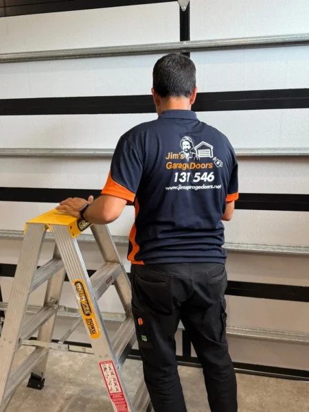 Garage door panel inspection with technician checking horizontal tracks and door alignment inside residential garage