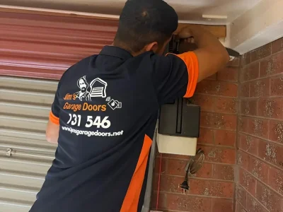 Technician repairing roller door opener by adjusting side mounted motor unit and control system